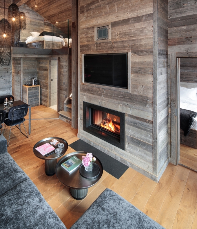 Le Penthouse Le Sommet offre un espace de vie chaleureux avec cheminée et vue sur les Alpes valaisannes.
