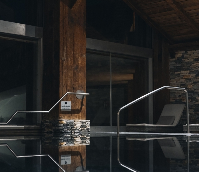 Piscine extérieure du Spa L'Alpage avec terrasse, transats et vue sur les montagnes à Crans-Montana.